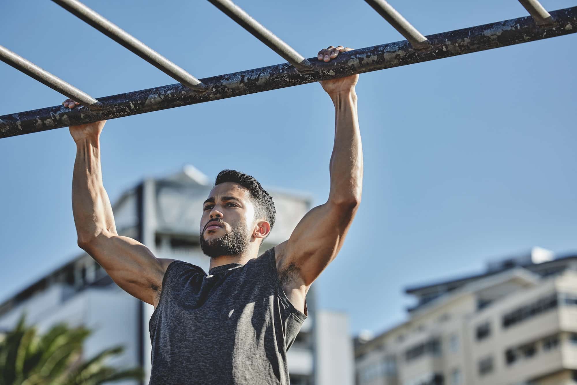 Always up for a challenge. Shot of a muscular young man exercising at a calisthenics park.