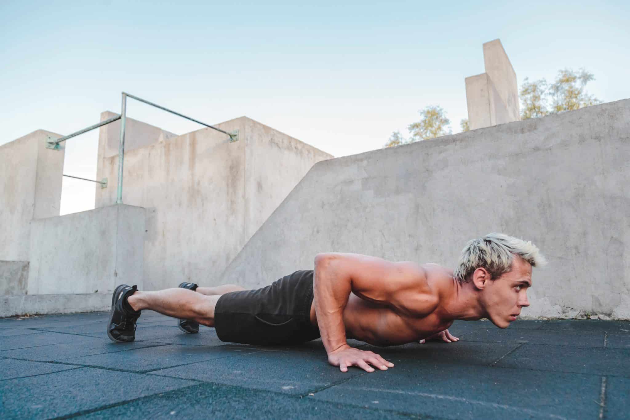 Young athletic man doing push ups on parkour area. Training alone outdoors.